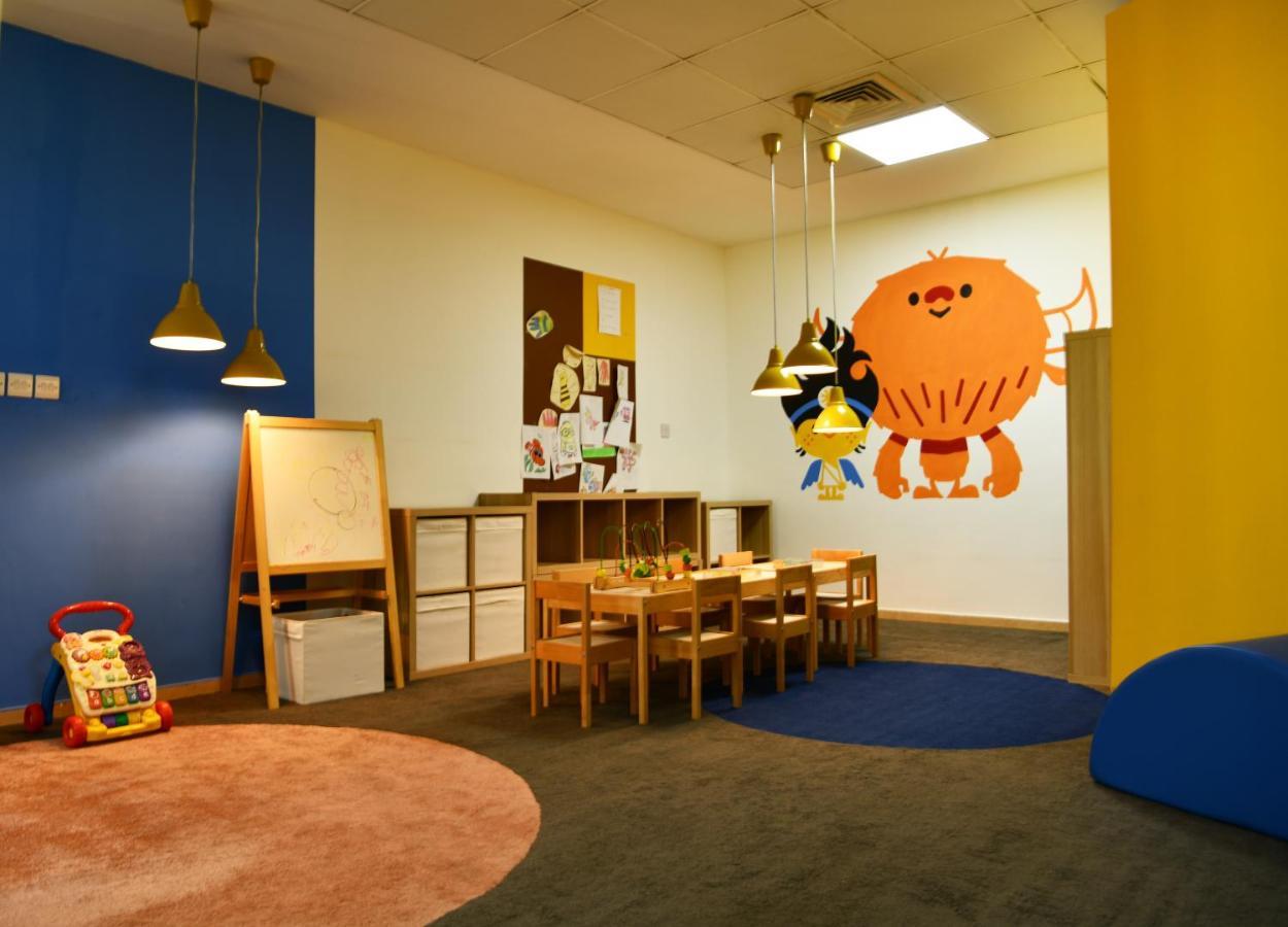 알 라하 비치 호텔 아부다비 외부 사진 The photo shows a colorful children's classroom or play area. The walls are painted in various shades, including blue and yellow. There is a large, playful character mural on one wall that appears to be a friendly monster. 

In the room, there is a s