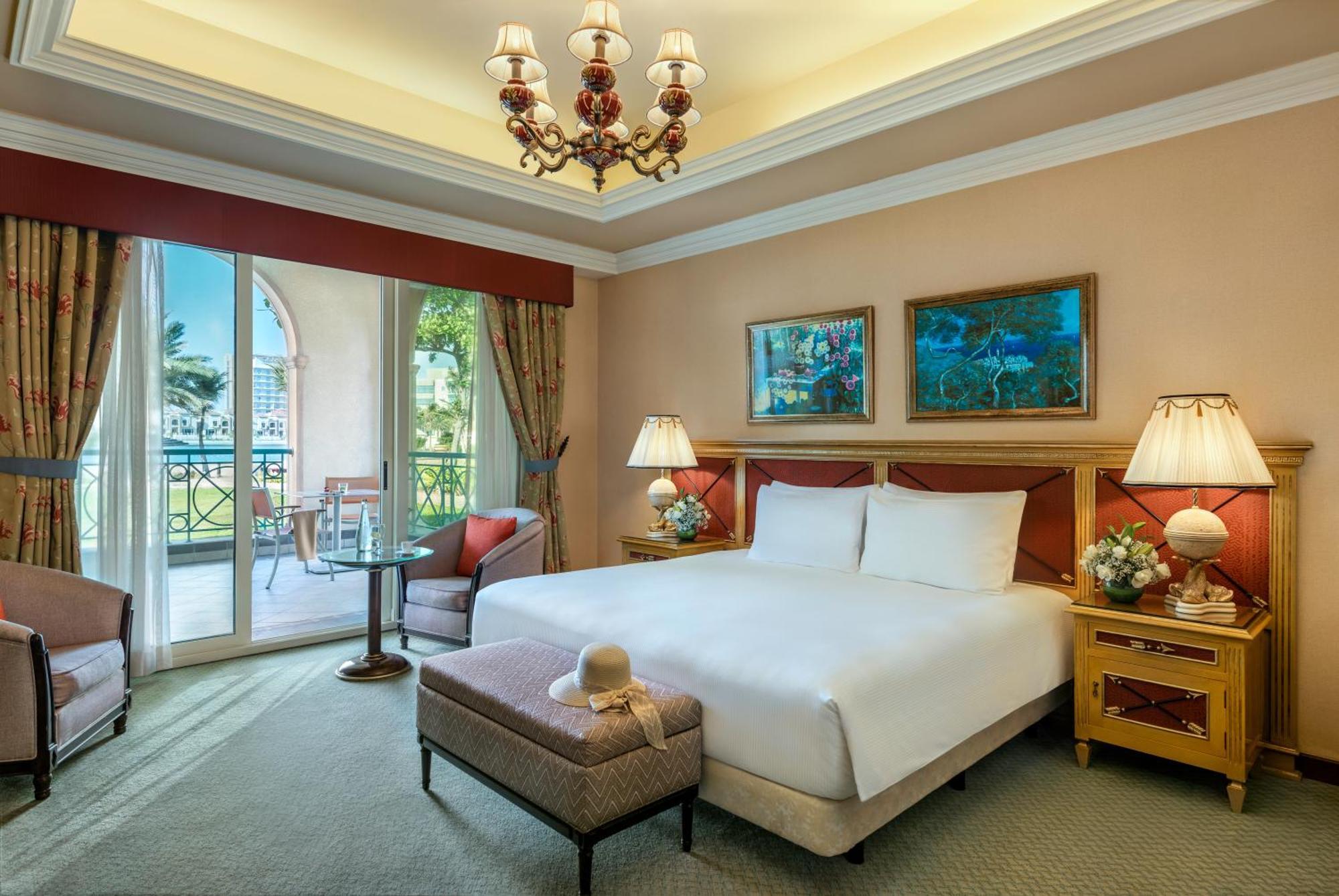 알 라하 비치 호텔 아부다비 외부 사진 The image depicts a well-furnished hotel room. It features a large bed with white linens, flanked by two bedside lamps. Above the bed, there are two pieces of artwork hanging on the walls. To the side, there is a comfortable armchair and a small tabl