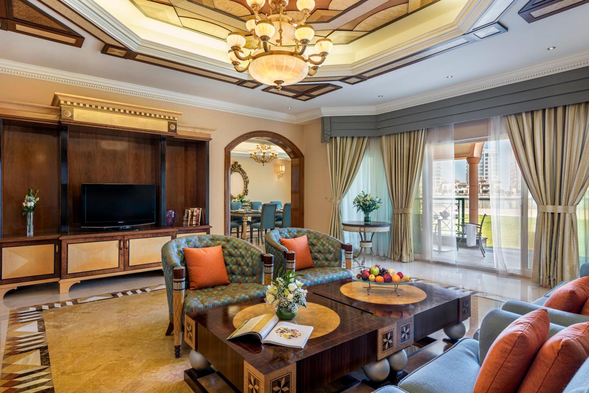 알 라하 비치 호텔 아부다비 외부 사진 The photo depicts a luxurious living room with elegant decor. It features two green upholstered sofas accented with orange pillows, arranged around a stylish coffee table. The coffee table showcases decorative items, including a magazine and a bowl o